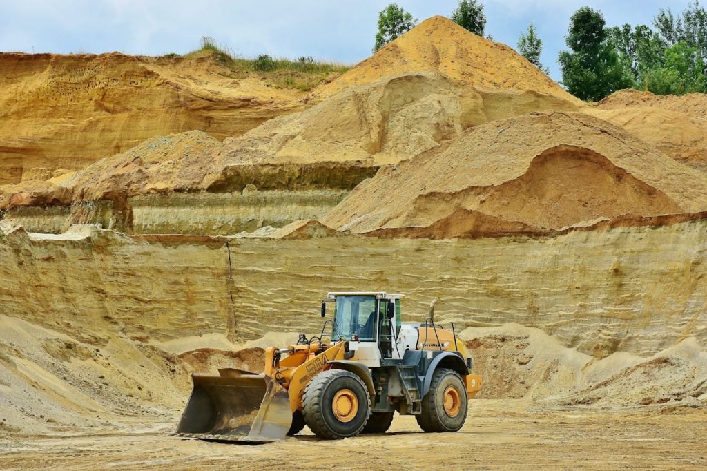 front-end-loader-461789 An excavator working in an open pit mine surrounded by sandy terrain and clear sky.